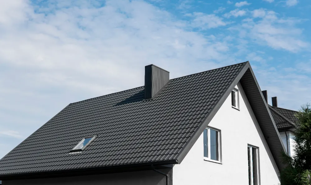 modern residential home with dark asphalt shingle roof installation showing clean lines, chimney, skylight, and long-term weather protection