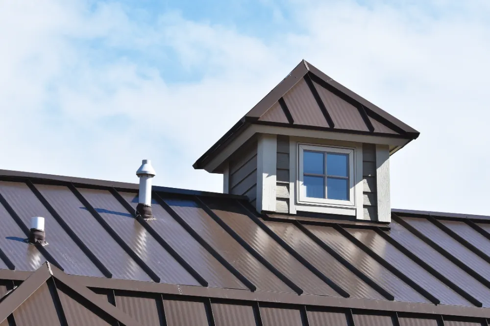 Brown ribbed metal roofing with dormer window on a Maine home, showing durable steel panels and precise installation.