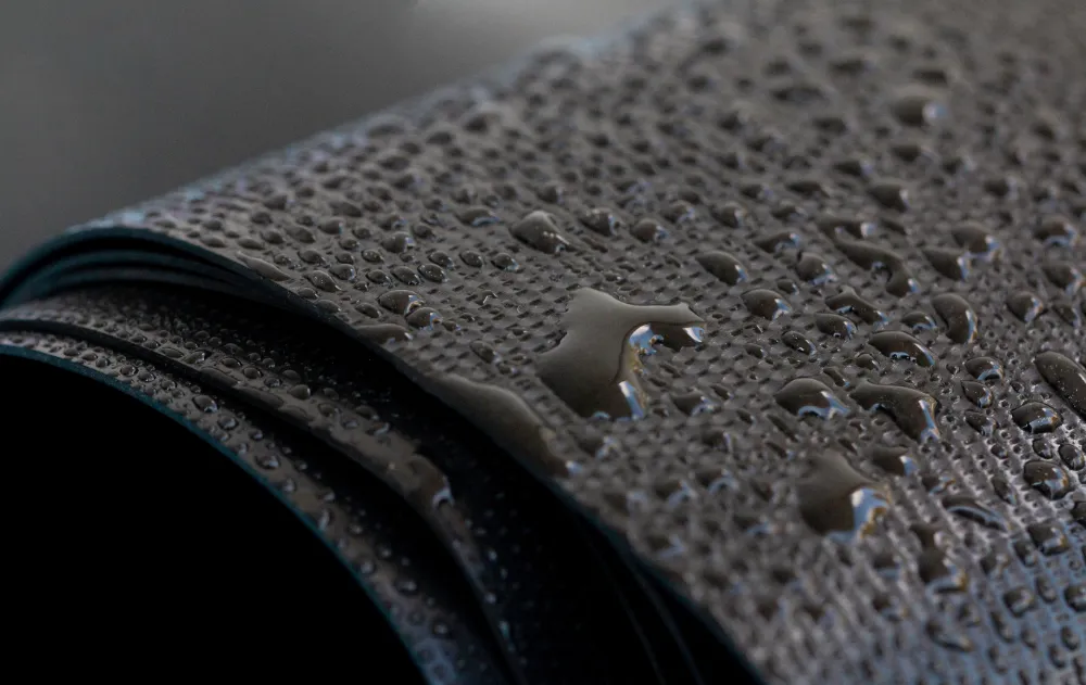 Close-up of EPDM rubber roofing membrane with water droplets showing its waterproof durability in Maine.
