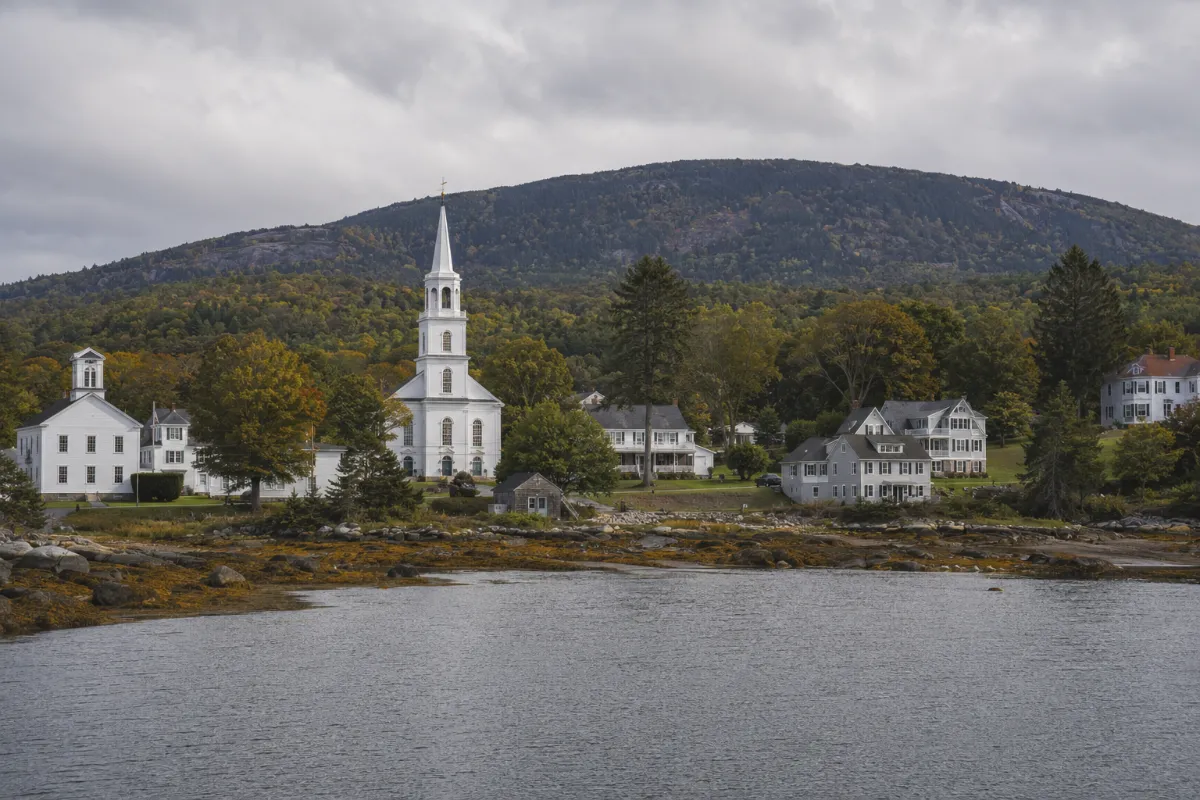 Blue Hill Maine village — white steepled church and salt-water farmhouses at the head of Blue Hill Bay, the rounded Blue Hill mountain rising behind