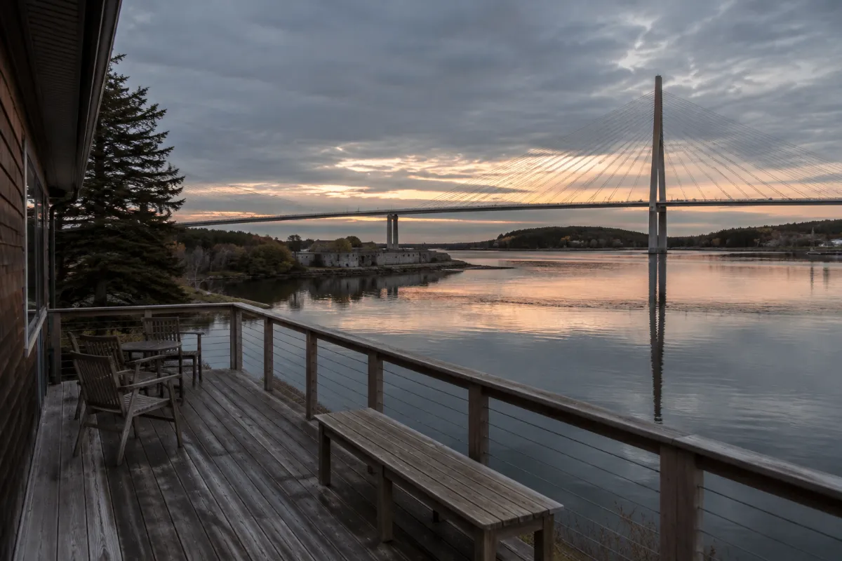 Riverfront deck in Bucksport facing Fort Knox and the Penobscot Narrows Bridge at dusk, reflections on the water