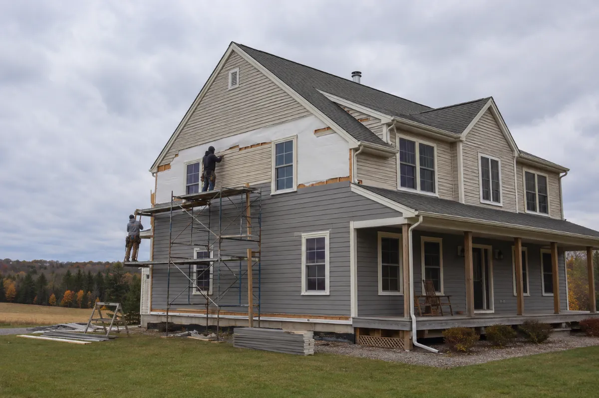Upgraded fiber-cement siding going onto a Hermon suburban home in place of faded vinyl, wide lawn and big sky