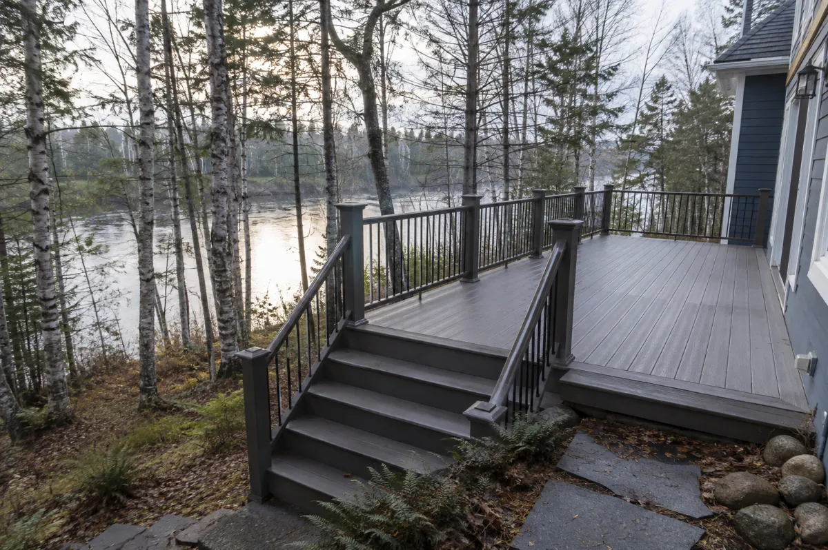 Backyard deck at an Orono home overlooking the Stillwater River through birches, morning light on the water