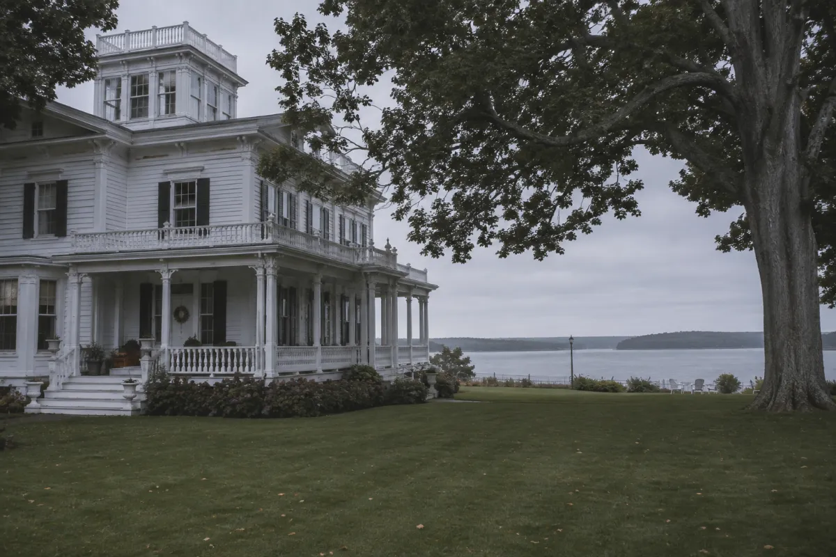 Historic white sea captain's mansion with a widow's walk on Searsport Maine's captains' row, big elms and a lawn running toward Penobscot Bay